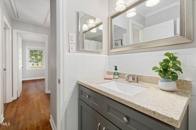 bathroom with ornamental molding, tile walls, hardwood / wood-style floors, and vanity