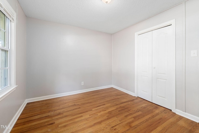 unfurnished bedroom featuring a closet, hardwood / wood-style flooring, and a textured ceiling