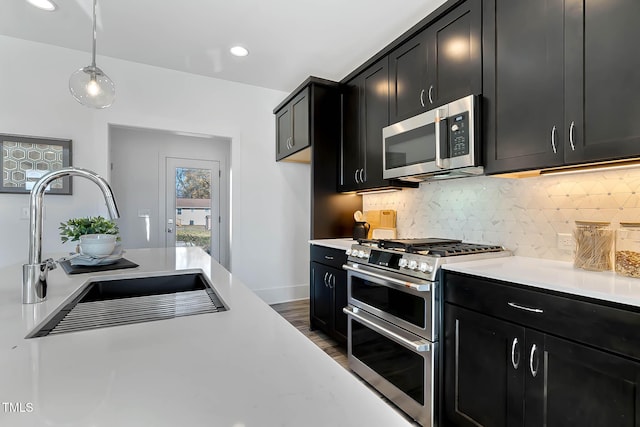 kitchen featuring sink, hanging light fixtures, dark hardwood / wood-style flooring, backsplash, and appliances with stainless steel finishes