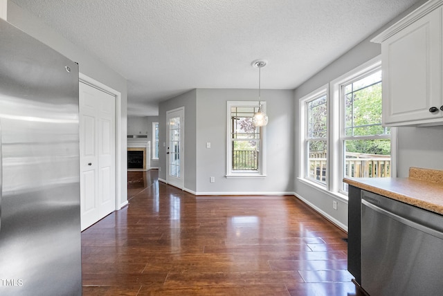 kitchen featuring white cabinetry, dark wood-type flooring, stainless steel appliances, a textured ceiling, and decorative light fixtures