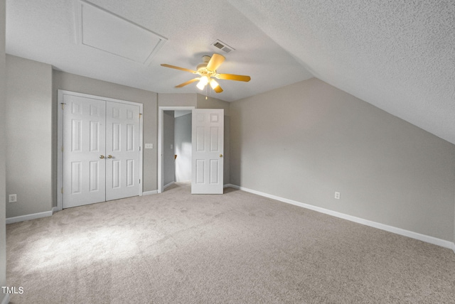 unfurnished bedroom featuring ceiling fan, carpet floors, vaulted ceiling, and a textured ceiling