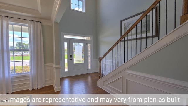 entrance foyer with ornamental molding, a wealth of natural light, and dark hardwood / wood-style floors