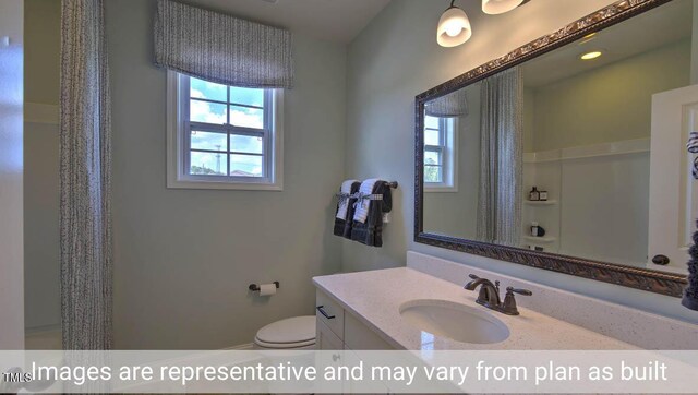 bathroom featuring walk in shower, vanity, and toilet