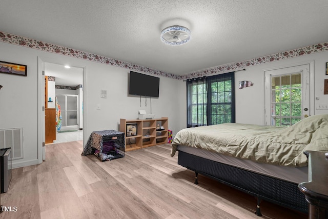 bedroom with light wood-type flooring, access to outside, and a textured ceiling