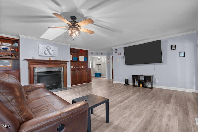 living room with light wood-type flooring, a textured ceiling, a fireplace, crown molding, and ceiling fan