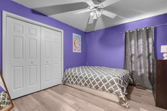 bedroom featuring a closet, light hardwood / wood-style floors, ceiling fan, and a textured ceiling