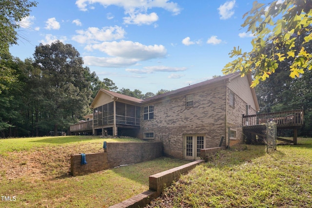 view of home's exterior with a lawn, a wooden deck, a sunroom, and french doors