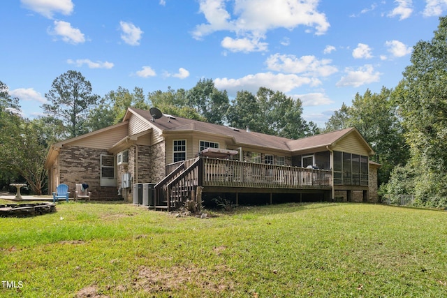 rear view of house with a sunroom, a wooden deck, and a yard