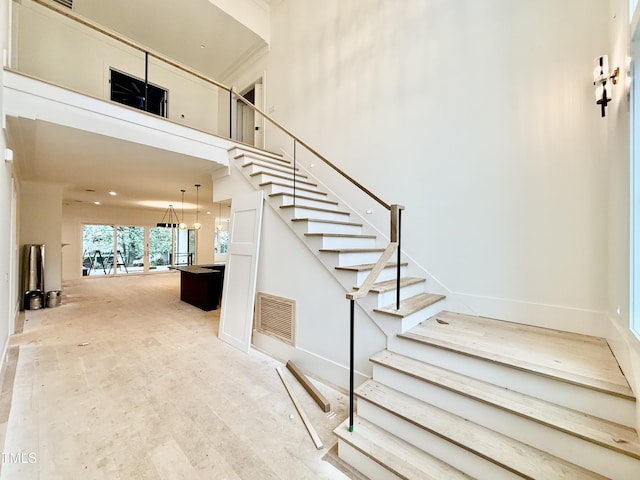 stairway featuring a towering ceiling and hardwood / wood-style floors