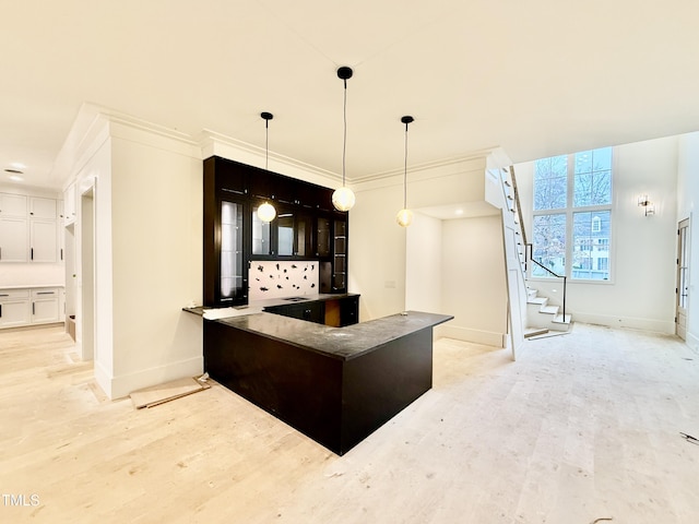 kitchen featuring hanging light fixtures, ornamental molding, and light wood-type flooring