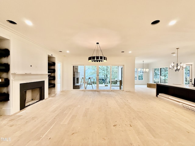 living room with ornamental molding, an inviting chandelier, and light hardwood / wood-style floors