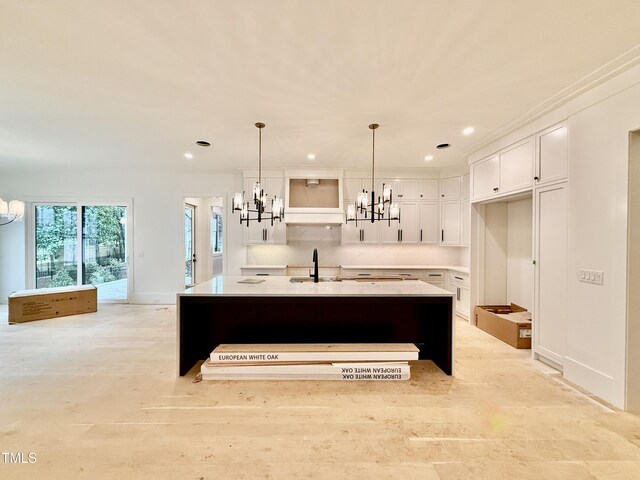 kitchen featuring a kitchen island with sink, hanging light fixtures, a notable chandelier, white cabinets, and decorative backsplash