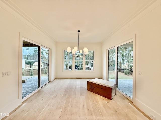 unfurnished dining area featuring an inviting chandelier, light hardwood / wood-style flooring, ornamental molding, and plenty of natural light