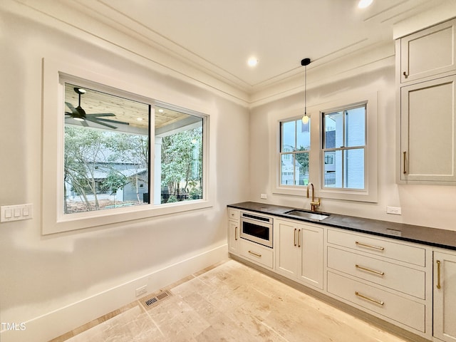 kitchen featuring sink, crown molding, decorative light fixtures, stainless steel microwave, and light hardwood / wood-style floors