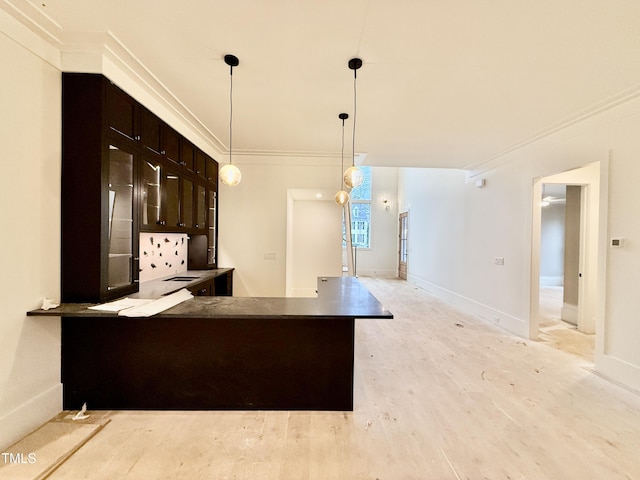 kitchen featuring dark brown cabinetry, crown molding, light hardwood / wood-style flooring, kitchen peninsula, and pendant lighting