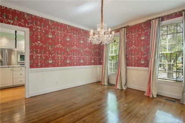 unfurnished room featuring hardwood / wood-style flooring, crown molding, and a chandelier