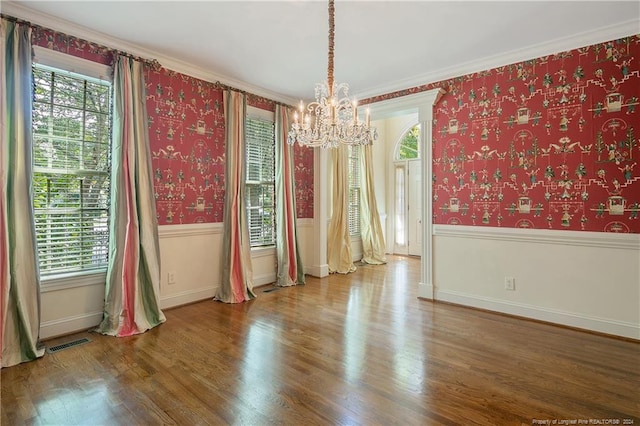 spare room with ornamental molding, an inviting chandelier, hardwood / wood-style floors, and a wealth of natural light