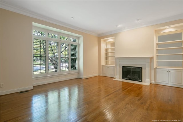 unfurnished living room with wood-type flooring, crown molding, and built in features