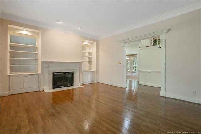 unfurnished living room with a fireplace, ornamental molding, dark wood-type flooring, and built in shelves