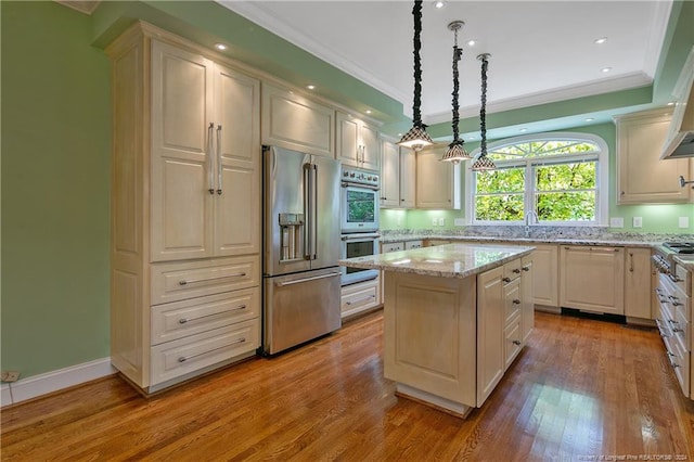 kitchen featuring hanging light fixtures, a kitchen island, light hardwood / wood-style flooring, appliances with stainless steel finishes, and light stone countertops