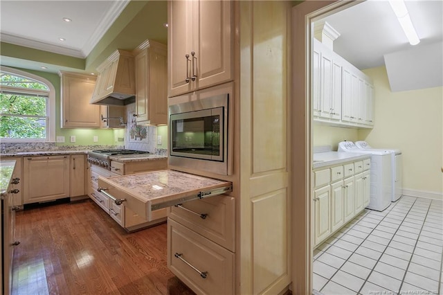 kitchen featuring custom exhaust hood, light hardwood / wood-style flooring, stainless steel appliances, independent washer and dryer, and ornamental molding