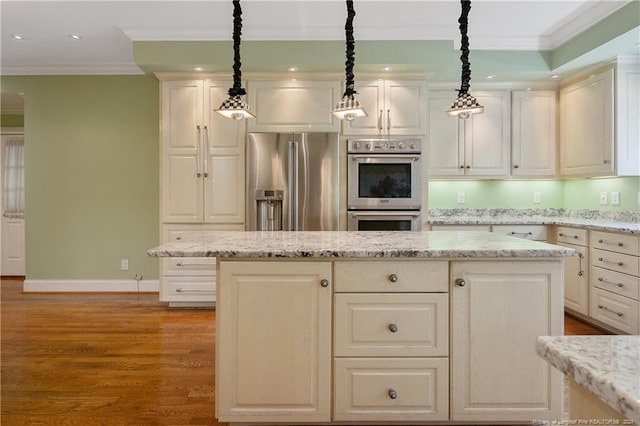 kitchen with light stone countertops, stainless steel appliances, light hardwood / wood-style floors, and hanging light fixtures