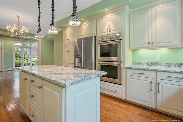 kitchen featuring light wood-type flooring, hanging light fixtures, ornamental molding, and stainless steel appliances