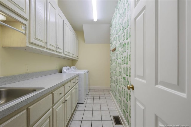 clothes washing area featuring washing machine and dryer, sink, light tile patterned floors, and cabinets