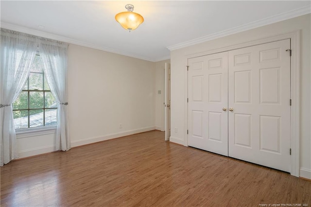 unfurnished bedroom featuring ornamental molding, a closet, and hardwood / wood-style floors