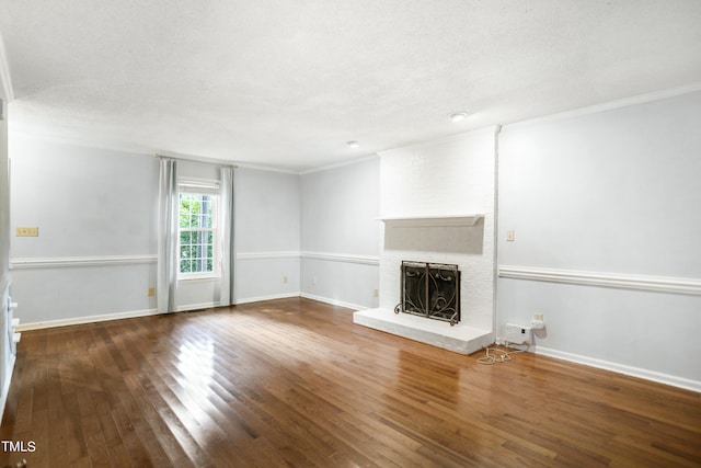 unfurnished living room with ornamental molding, a brick fireplace, wood-type flooring, and a textured ceiling