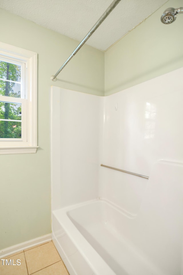 bathroom with a textured ceiling, washtub / shower combination, and tile patterned floors