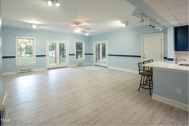 living room with sink, ceiling fan, a baseboard heating unit, and light hardwood / wood-style floors