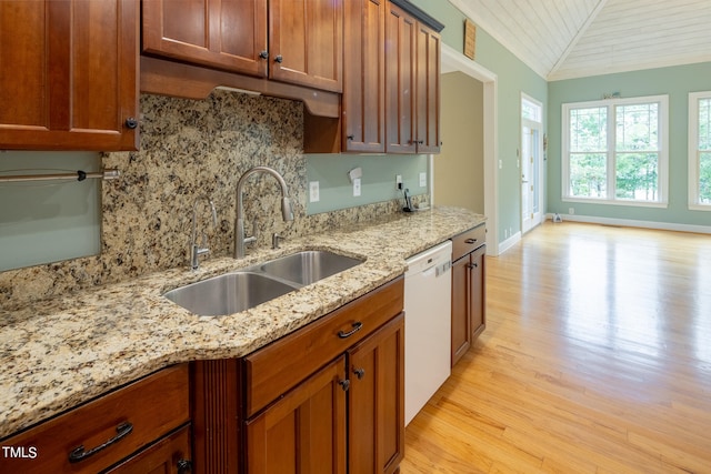 kitchen featuring light stone counters, sink, light hardwood / wood-style floors, vaulted ceiling, and dishwasher