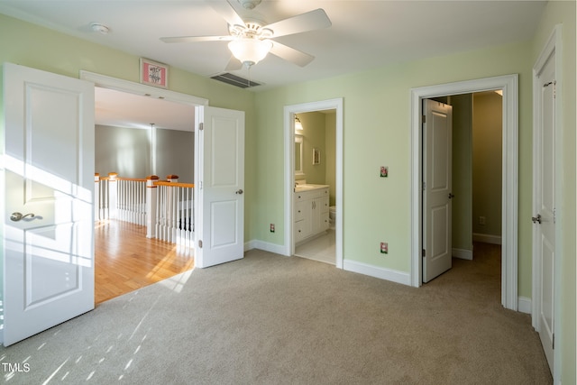 unfurnished bedroom featuring light carpet, ensuite bath, and ceiling fan