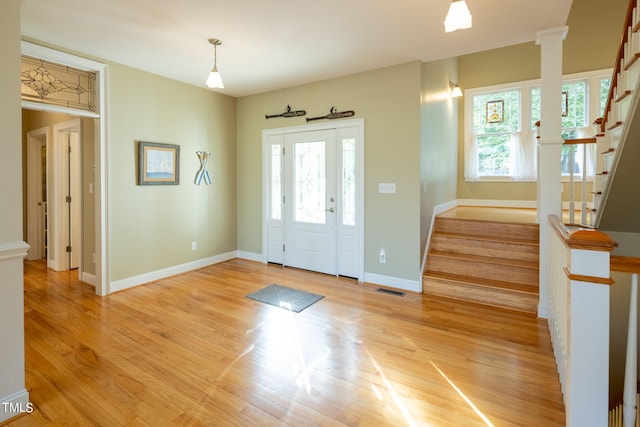 entrance foyer with decorative columns, light wood-type flooring, and a wealth of natural light