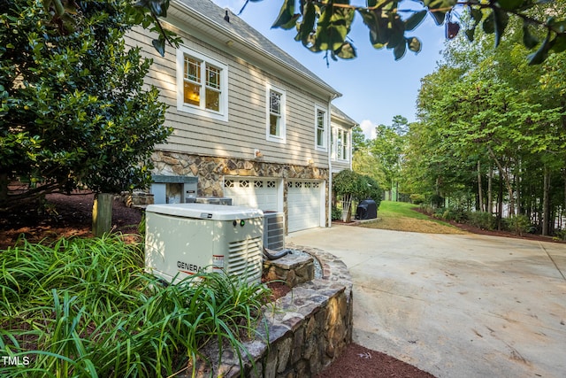 view of home's exterior with central AC unit and a garage