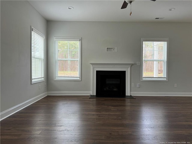 unfurnished living room featuring ceiling fan, dark hardwood / wood-style floors, and a healthy amount of sunlight