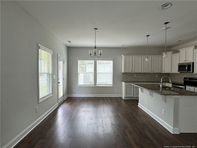 kitchen with white cabinets, a breakfast bar area, appliances with stainless steel finishes, and hanging light fixtures