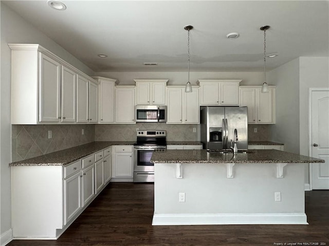 kitchen featuring dark stone countertops, pendant lighting, stainless steel appliances, and dark hardwood / wood-style flooring