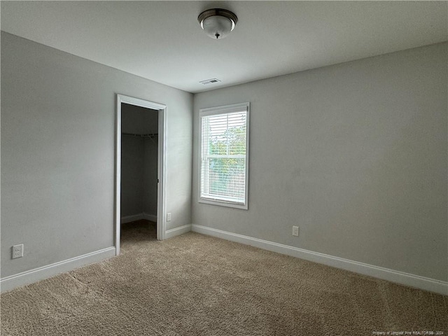 unfurnished bedroom with carpet flooring, a spacious closet, and a closet