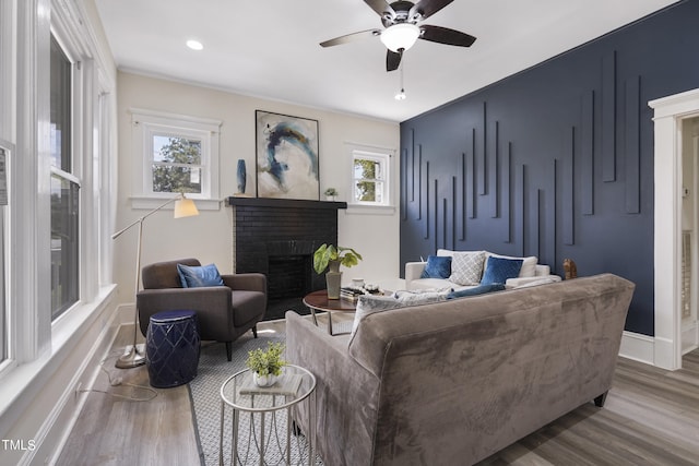 living room featuring ceiling fan, hardwood / wood-style flooring, plenty of natural light, and a fireplace