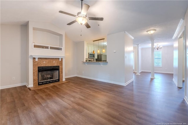 unfurnished living room with dark wood-style flooring, baseboards, ceiling fan with notable chandelier, and a tile fireplace