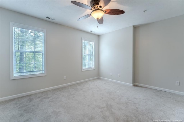 carpeted spare room with visible vents, baseboards, and ceiling fan