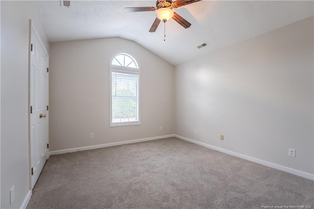 spare room featuring carpet floors, ceiling fan, lofted ceiling, and visible vents