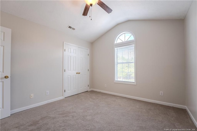 unfurnished bedroom with carpet flooring, baseboards, visible vents, and lofted ceiling