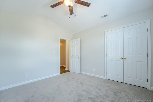 unfurnished bedroom with visible vents, a closet, lofted ceiling, baseboards, and carpet