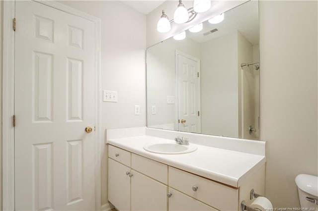 bathroom with vanity, toilet, and visible vents
