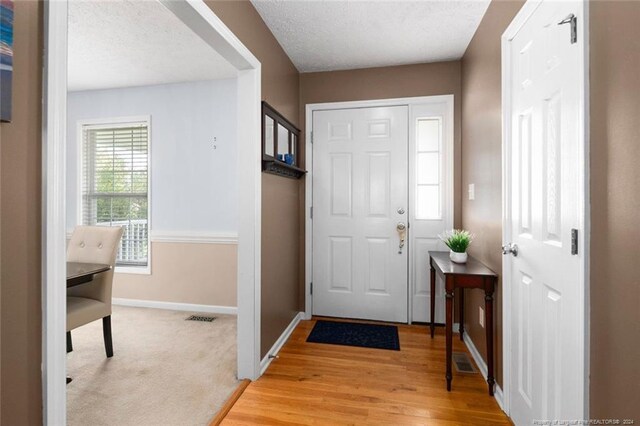 foyer with a textured ceiling and light hardwood / wood-style flooring