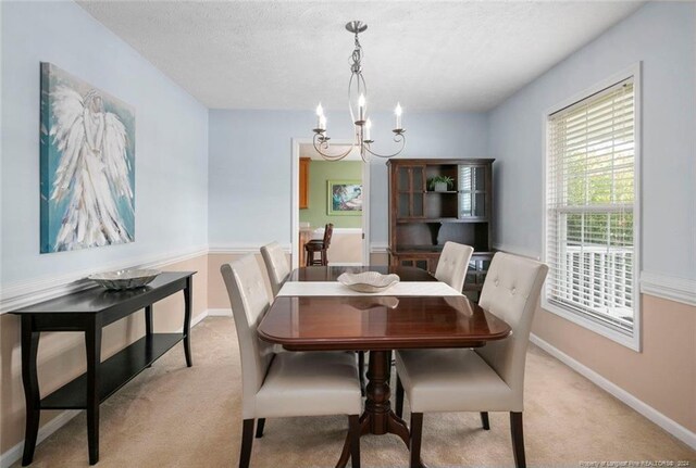 carpeted dining space featuring a notable chandelier and a textured ceiling