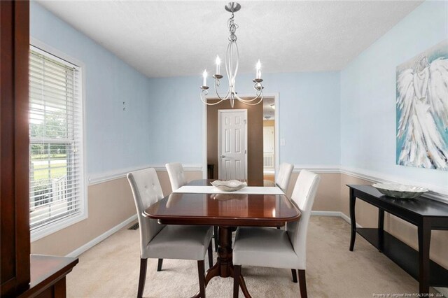 dining space with light colored carpet, an inviting chandelier, and a textured ceiling